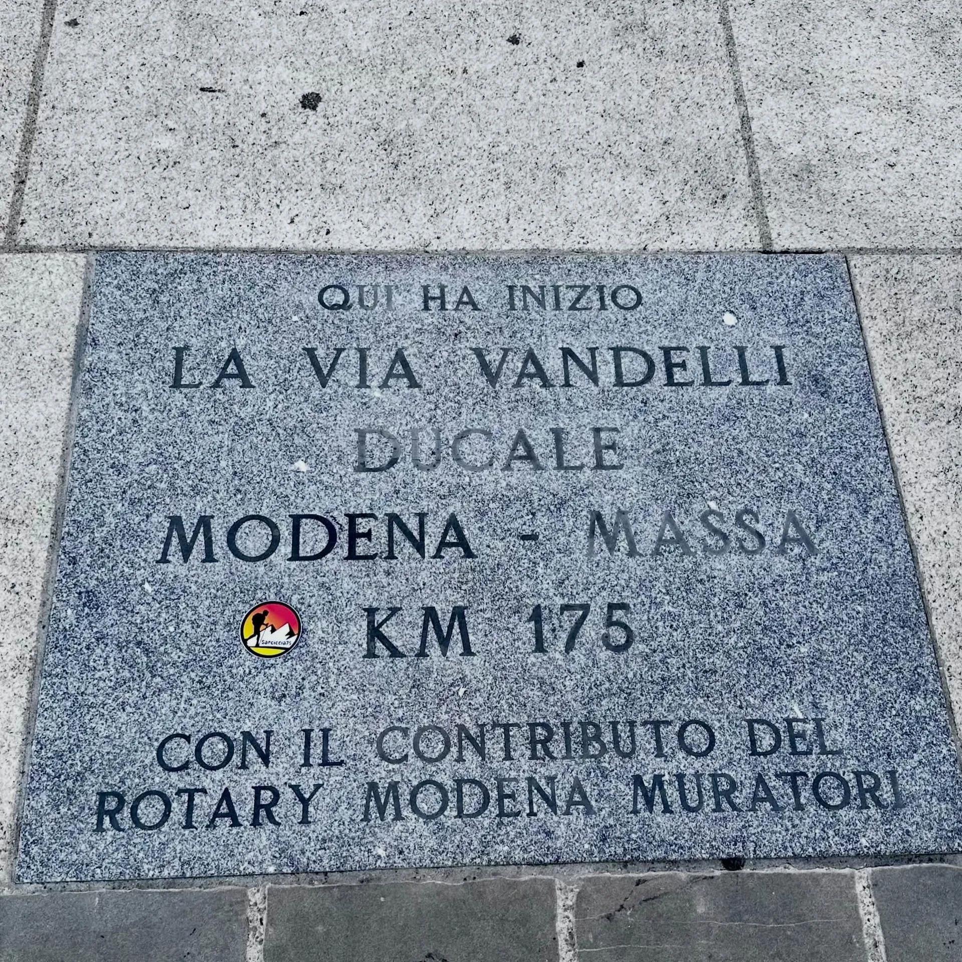 Lastra di pietra incisa che segna l'inizio della Via Vandelli, con la dicitura sul contributo del Rotary Modena Muratori e un adesivo con la sagoma di un escursionista